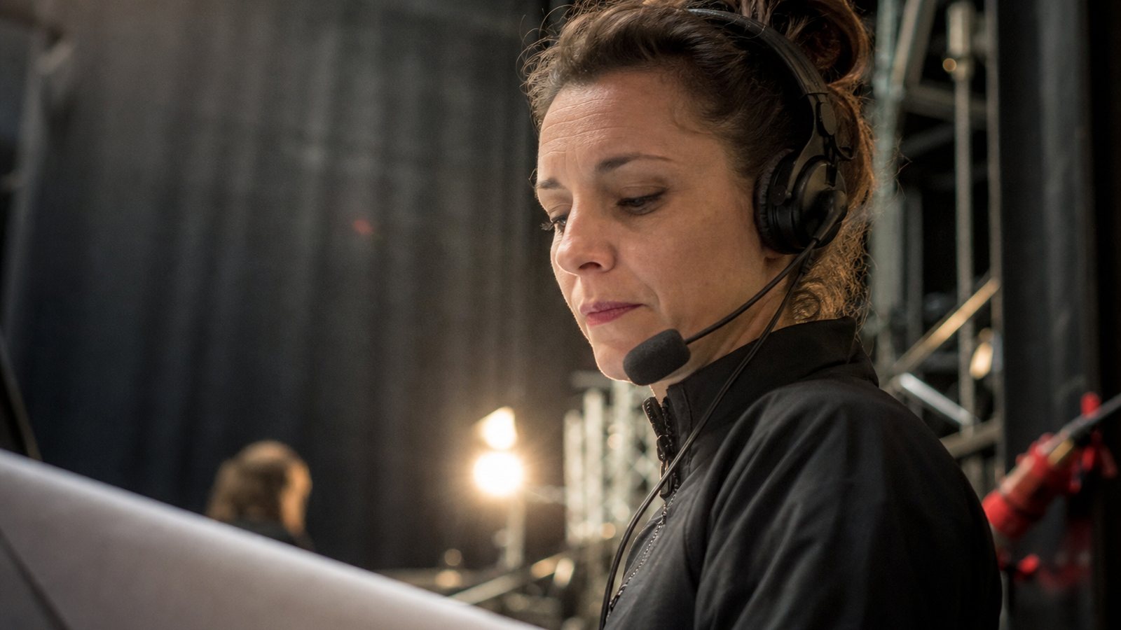Régisseur en coulisses coordonnant le déroulé du spectacle avec un casque et sa feuille de route